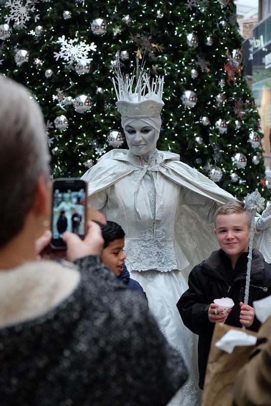 Snow Queen surrounded by joyful children, a moment of happiness captured in a picture. Smiles and a heartwarming Christmassy atmosphere at the London shopping mall's Christmas event.